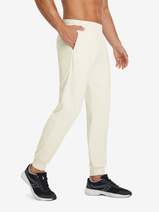 Side view of model with hand in pocket wearing lightweight traning track pants in cream.