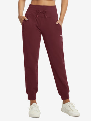 Model wearing women's stretch fleece lined water resistant joggers in wine, showcasing the front lower body view.