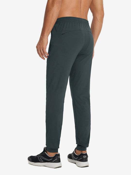 Back lower-body view showing lightweight traning track pants on model in dark grey.