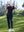 Model in navy women's performance solid polo holding a golf club outdoors