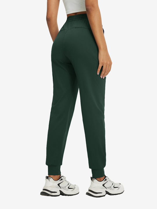 Back view of lightweight women's stretchy joggers sweatpants on model, shown in forest green.
