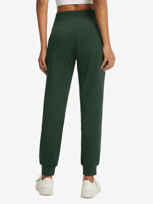 Model wearing women's stretch fleece lined water resistant joggers in forest green, showing the back lower body view.