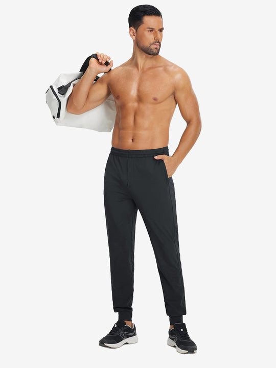 Model holding tennis racket wearing lightweight traning track pants in black.