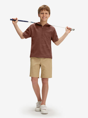 Full-body shot of model holding a golf club in coffee brown water-resistant short sleeve q-zip hoodie for boys