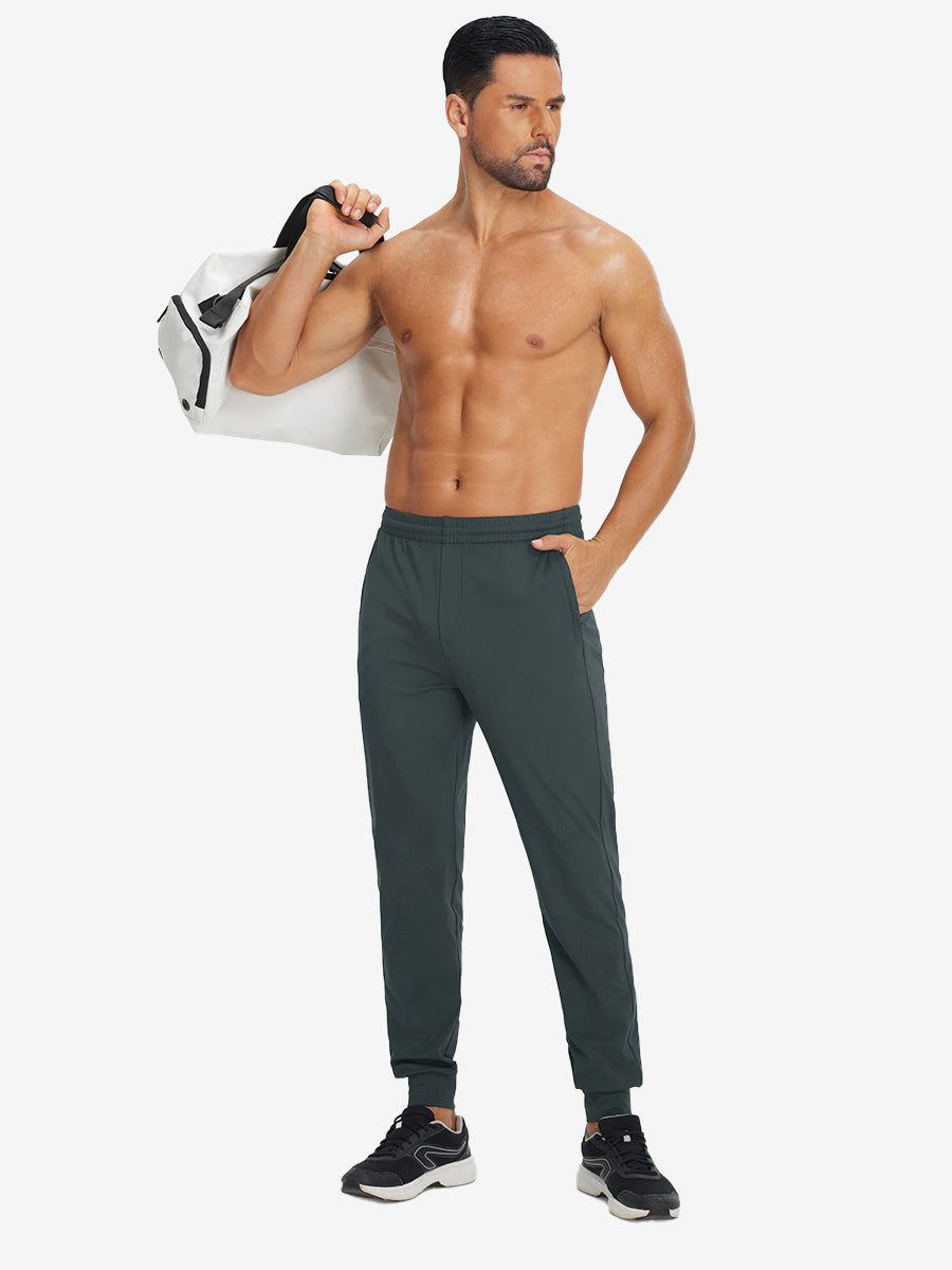 Model holding tennis racket wearing lightweight traning track pants in dark grey.