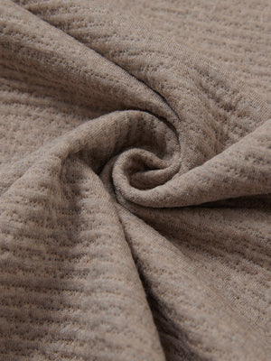 Close-up of fabric on textured insulated winter jacket, showing texture and finish in light brown heather.