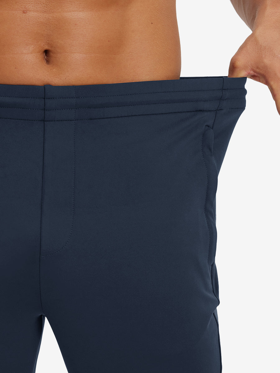 Model stretching waistband to show fit of lightweight traning track pants in navy.