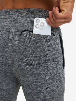 Close-up of iPhone partly inside pocket of black heather soft sweatpants with 4 zipper pockets