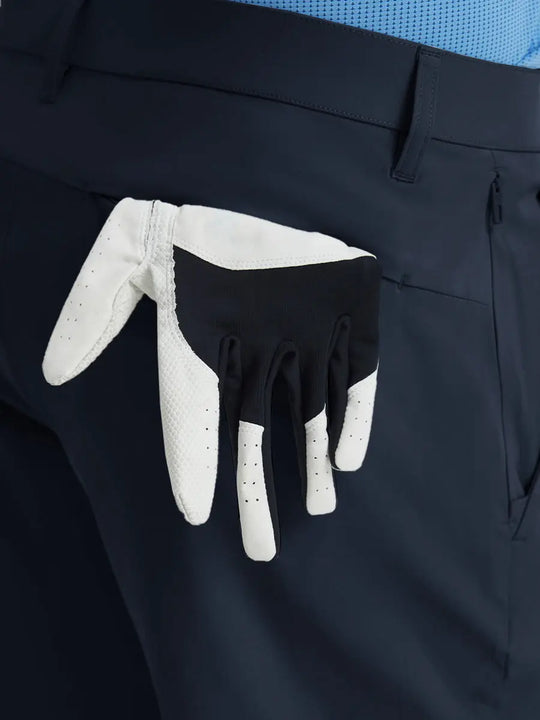 Back view of Player Fit Versatile Solid Shorts 9 Inch with golf glove tucked into right pocket – NAVY