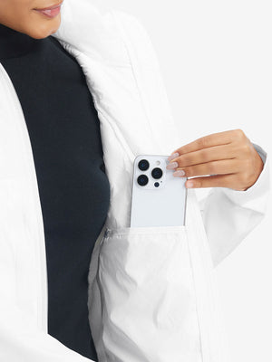 Hand placing an iPhone into pocket of women's lightweight fleece-lined puffer jacket in white.