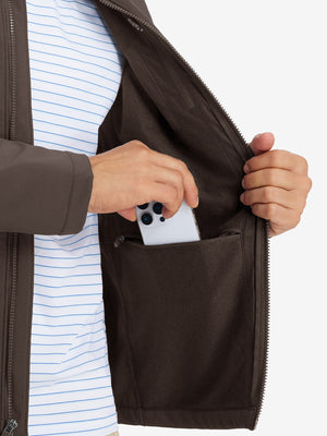 Close-up of winter thermal outdoor water resistant fleece jacket pocket holding a phone, practical detail in coffee brown