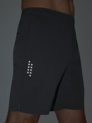 Detail of glow in the dark feature on dark grey breathable running shorts with 4 zipper pockets