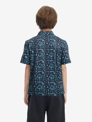 Back half-body view of youth wearing navy ocean beach performance print boys golf polo, showing rear design